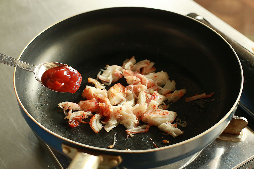 サラダ油を熱しにんにくのみじん切りと、かにかまを炒めケチャップで味付けをする